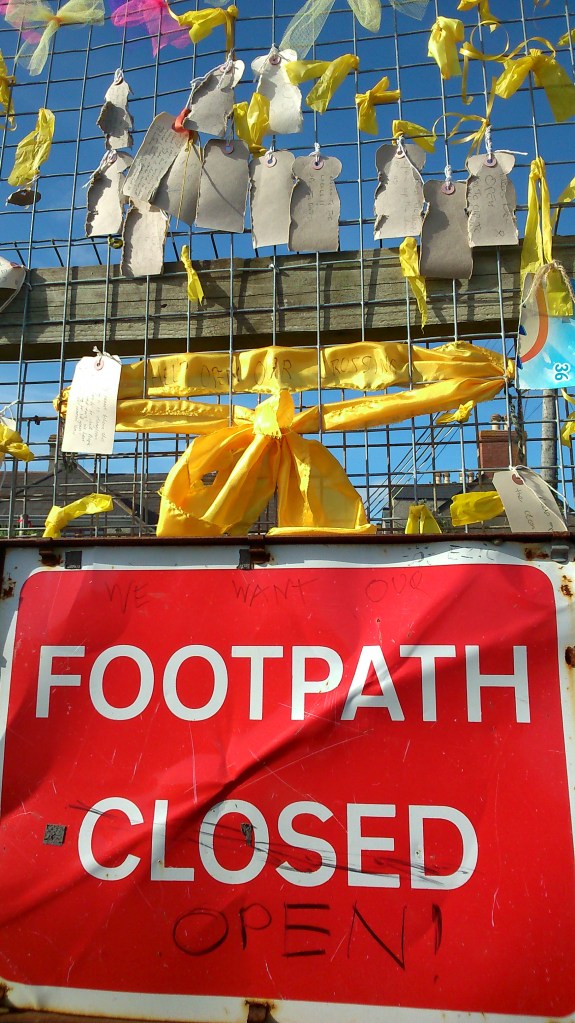 Photo of Long Rock Yellow Ribbon showing tags, ribbons and subverted sign.